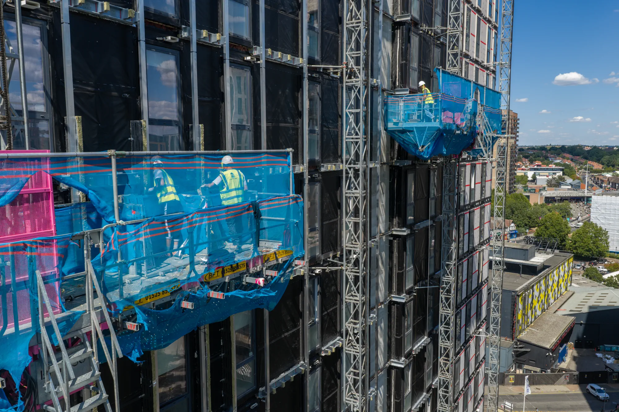Close aerial view of operatives carrying out facade works at height on Grand Felda House in Wembley