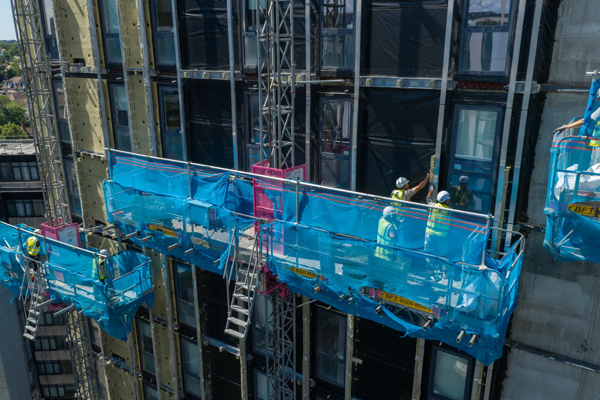 Operatives working from external access platforms during facade installation at Grand Felda House in Wembley